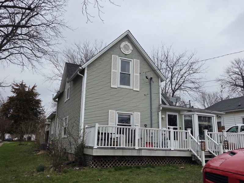Close-up of an asphalt shingle roof with a white chalk circle marking a small hail impact spot on the surface